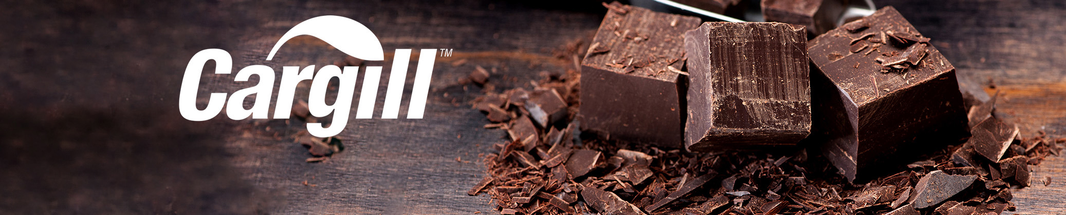Cargill logo next to dark chocolate chunks and shavings on wooden surface.