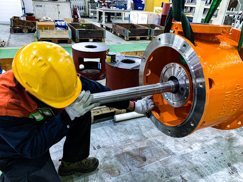Arbeider installerer aksel i DESMI pumpehus for væskehåndtering.