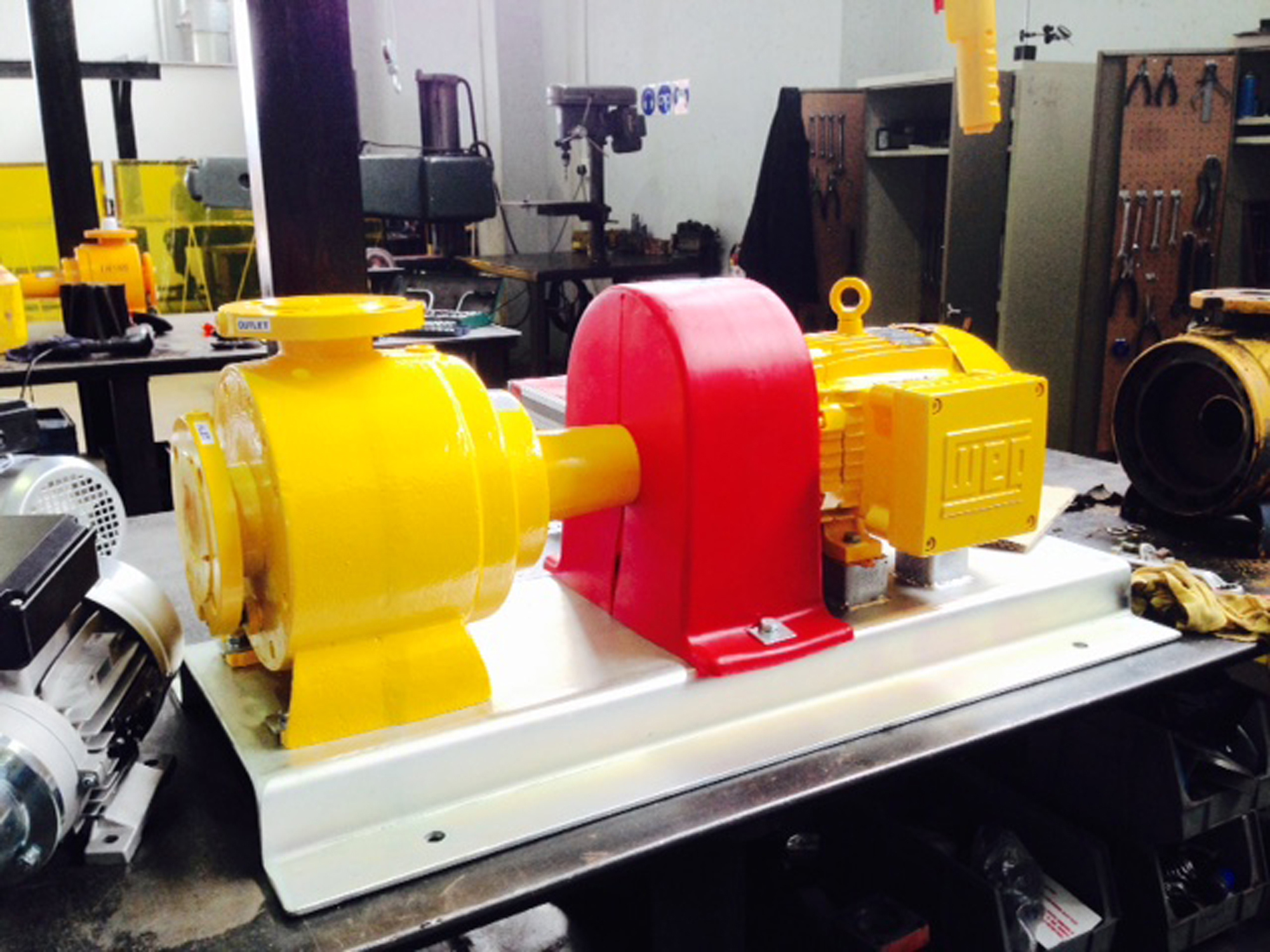 Yellow and red industrial pump on a workshop table for fluid handling.