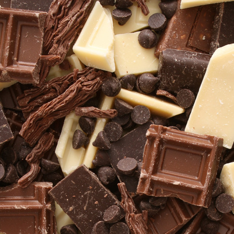 Różnorodne kawałki białej, mlecznej i ciemnej czekolady z wiórkami czekoladowymi w stosie.