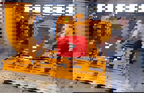 Hombre ajustando una gran bomba amarilla DESMI en un entorno industrial.