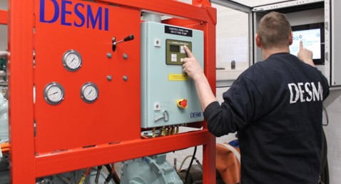 Technician operates control panel on DESMI pump system for fluid handling operations.