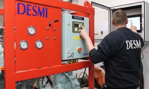 Technician operates control panel on DESMI pump system for fluid handling operations.