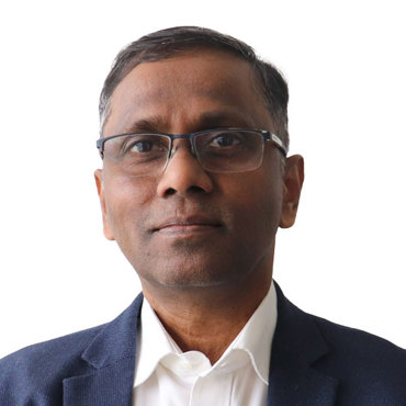 A person wearing glasses and a suit, posing against a plain background.