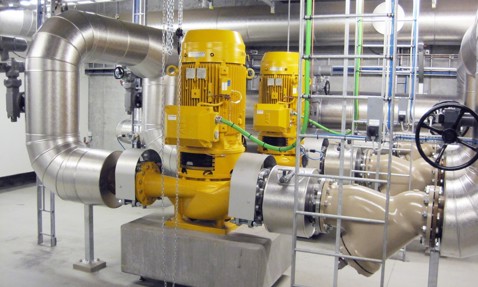 Industrial pumps and large pipes in a mechanical room for fluid handling.