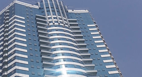 Modern high-rise building with reflective glass facade under clear blue sky.