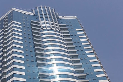 Modern high-rise building with reflective glass facade under clear blue sky.
