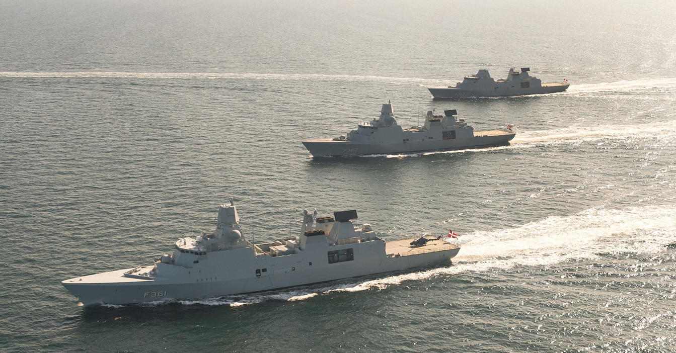 Three navy ships sailing in formation on open water.