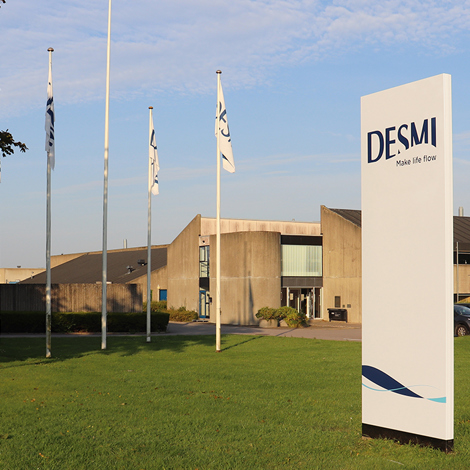 DESMI headquarters with flags and signage on a sunny day.