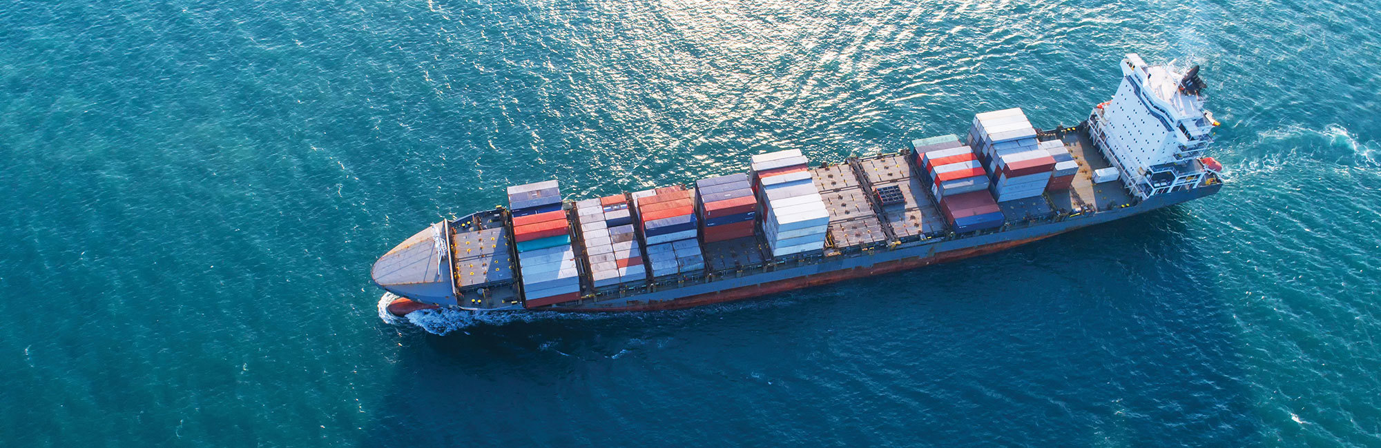 Aerial view of a cargo ship transporting colorful containers on the ocean.