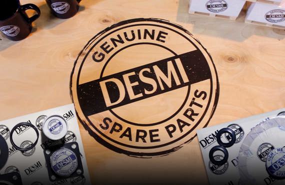Logo des pièces de rechange d'origine DESMI sur une surface en bois avec des tasses et des composants.
