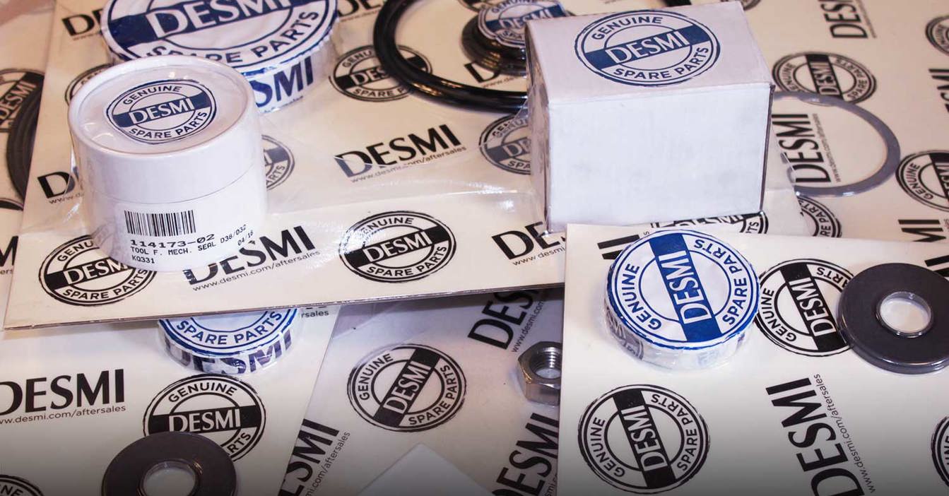 Piezas de repuesto genuinas de DESMI, incluidas juntas y etiquetas, expuestas sobre una mesa.