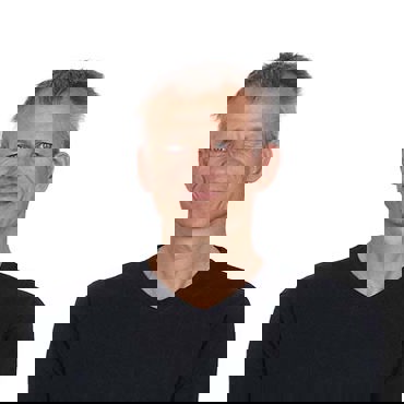 Smiling man in a black shirt against a white background.