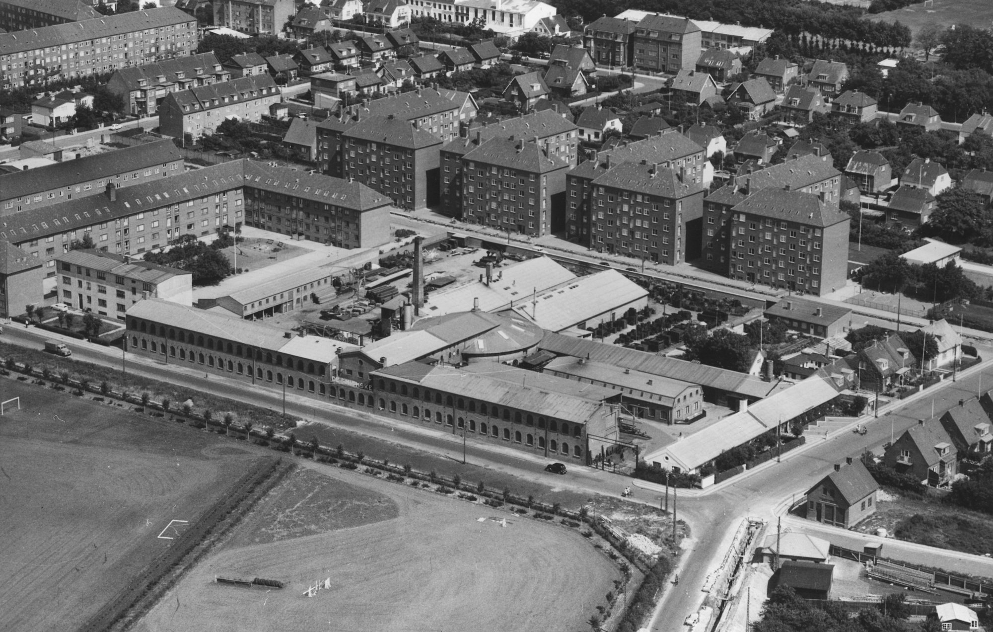 Aerial view of an industrial area with surrounding residential buildings and fields.