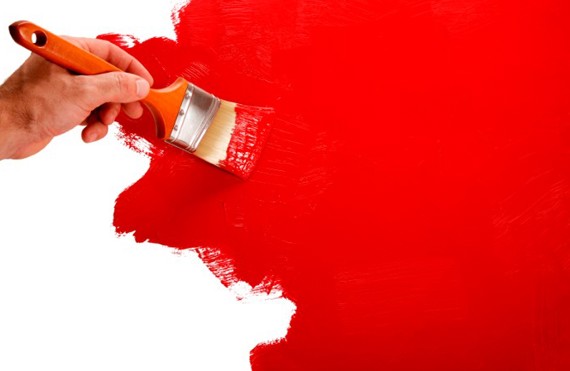 Hand painting a wall red with a paintbrush, leaving a smooth finish.