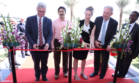 一群人在户外仪式上剪红色丝带。