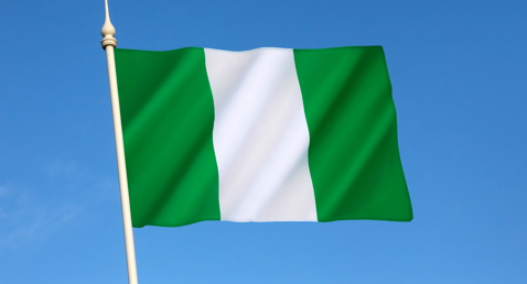 Nigerian flag waving against clear blue sky.