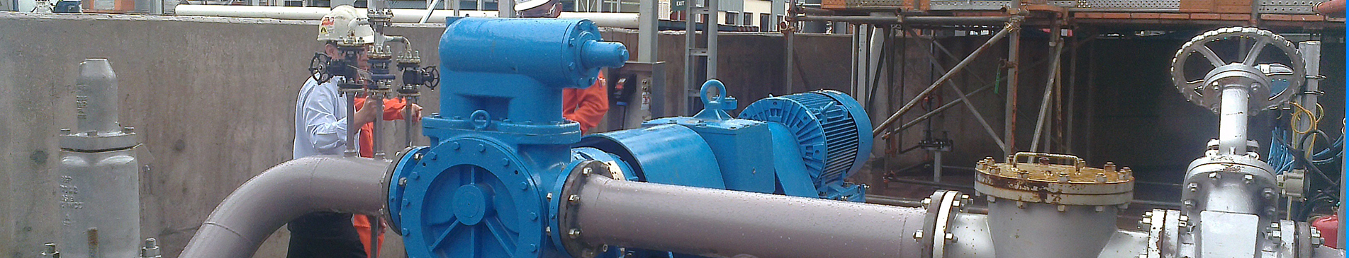 Blue industrial pump with pipes and workers in protective gear.