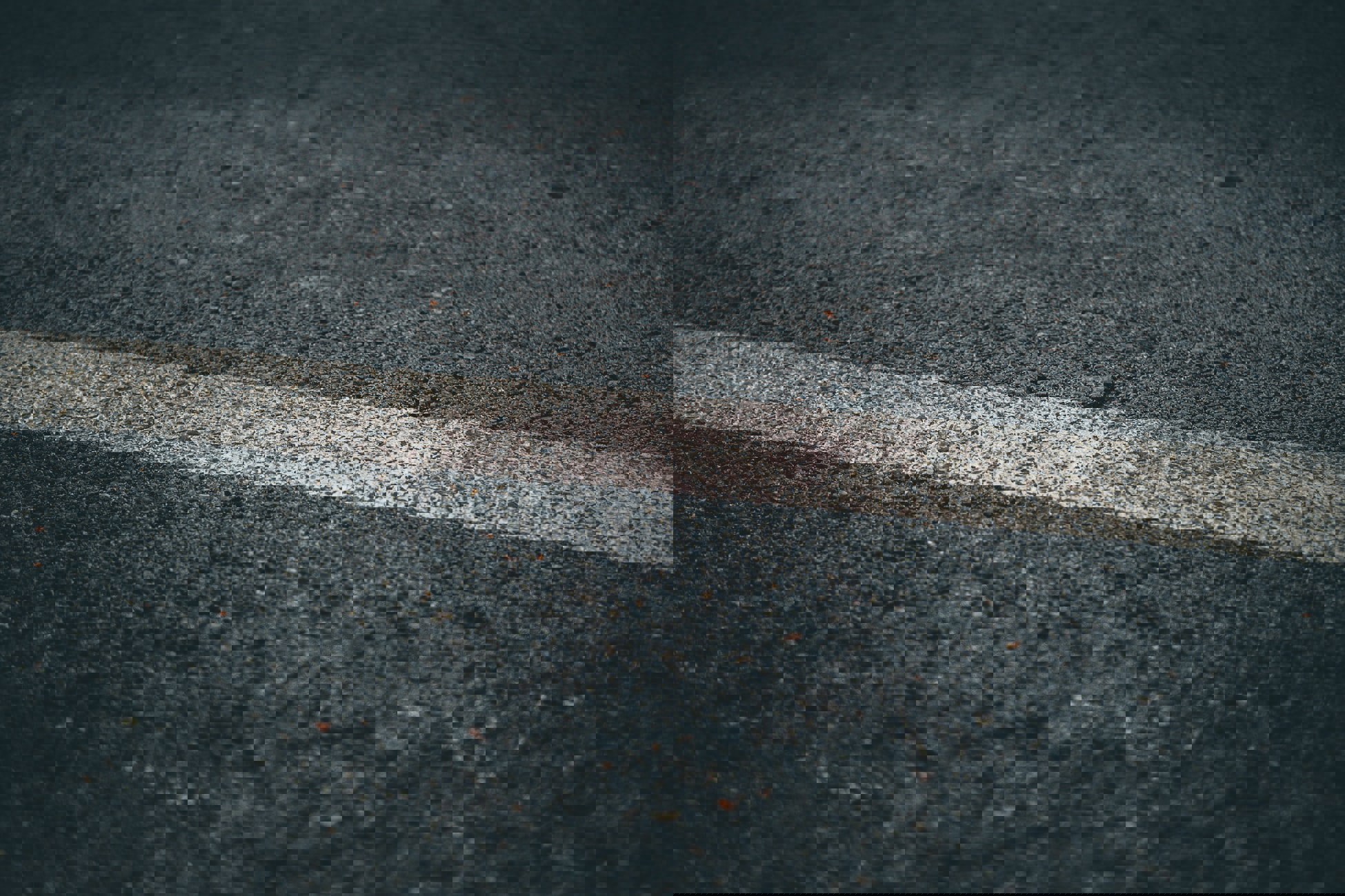Close-up of a road with a single white line on dark asphalt.