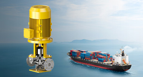 Yellow DESMI pump with a cargo ship in the background on the ocean.