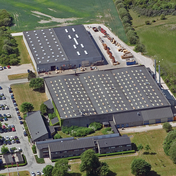 Aerial view of an industrial facility with parking and surrounding greenery.