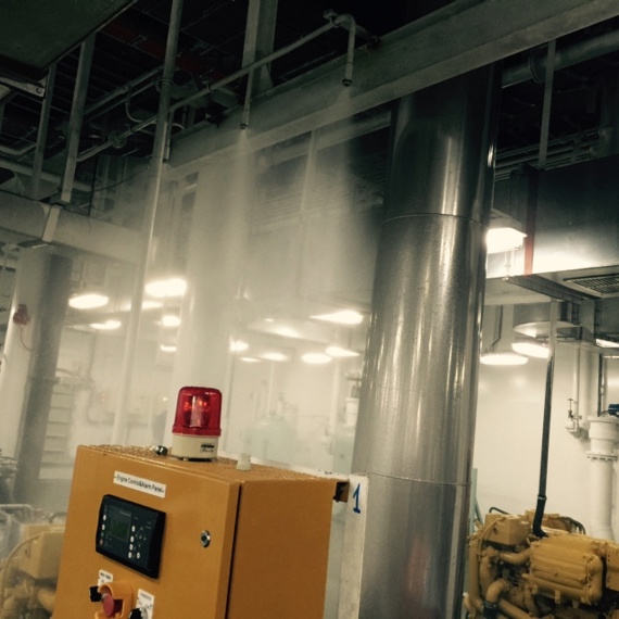 Industrieraum mit aktivem Sprinklersystem und Schalttafel mit rotem Licht.