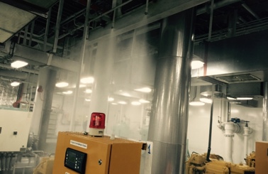 Industrieraum mit aktivem Sprinklersystem und Schalttafel mit rotem Licht.