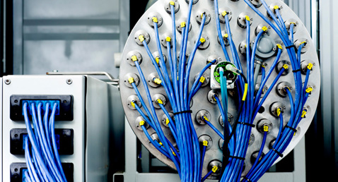 Industrial equipment with multiple blue cables connected to circular panel.