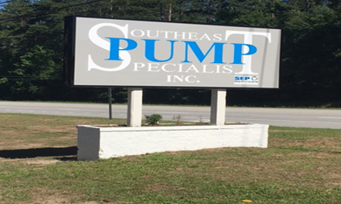 Sign for Southeast Pump Specialist Inc. stands by roadside with trees behind.