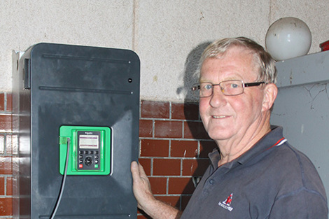 男子站在墙上安装的电子设备旁。