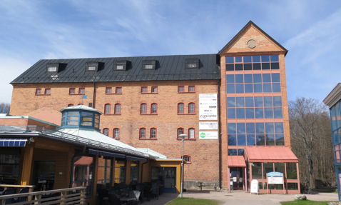 Historic brick building with modern glass extension under a blue sky.