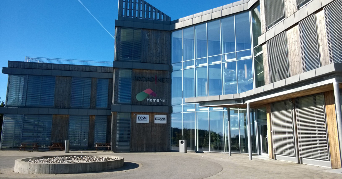 Modern building with glass facade and DESMI signage on a sunny day.