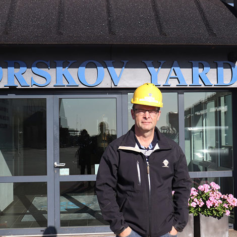 Man in a yellow hard hat stands in front of Orskov Yard entrance.