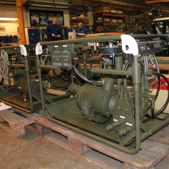 Industrial equipment on pallets in a warehouse with workers in the background.