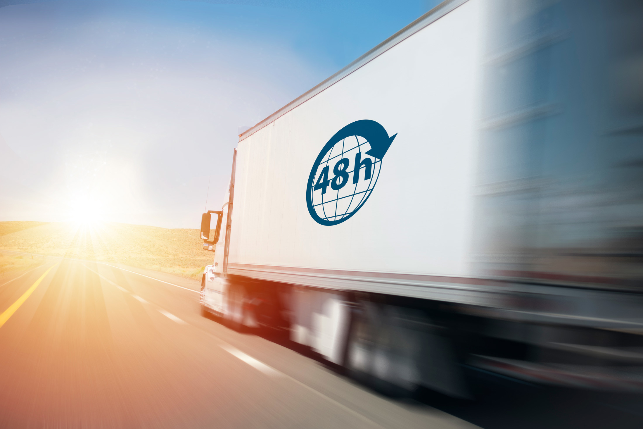 Camion con logo "48h" che guida su un'autostrada soleggiata.