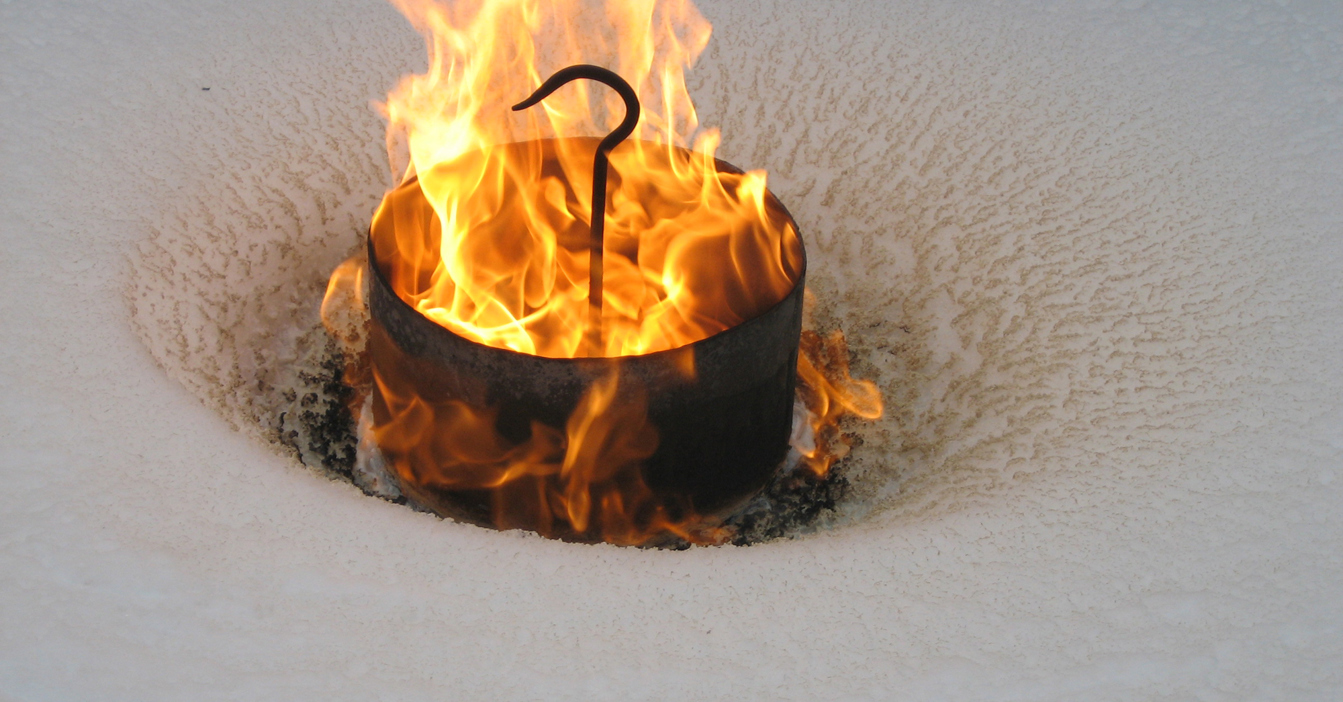 金属桶中燃烧的火焰，周围被雪覆盖。