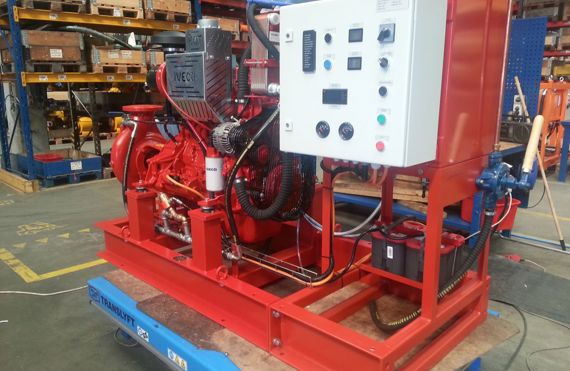 Red industrial pump system with control panel in a warehouse setting.