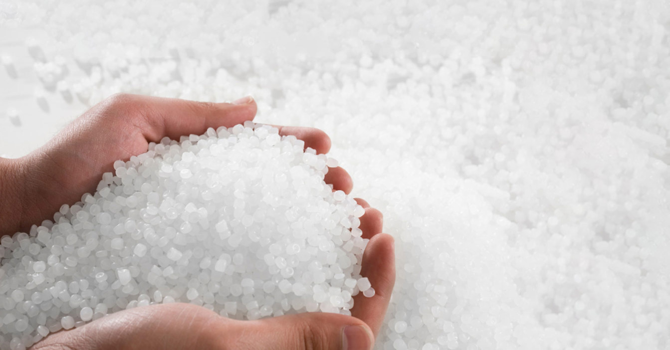 Hands holding a pile of white plastic pellets.