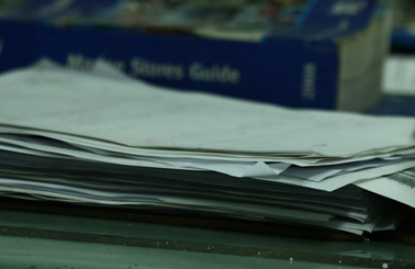 DESMI hard hat and stack of papers on a desk in an industrial setting.
