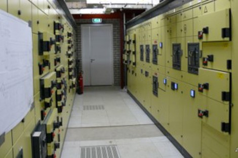 Industrial control room with yellow electrical panels and safety equipment.