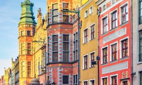 Colorful, historic European buildings with ornate facades and decorative towers under blue sky.