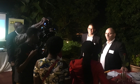 People gathered around a camera filming two individuals outdoors at night.