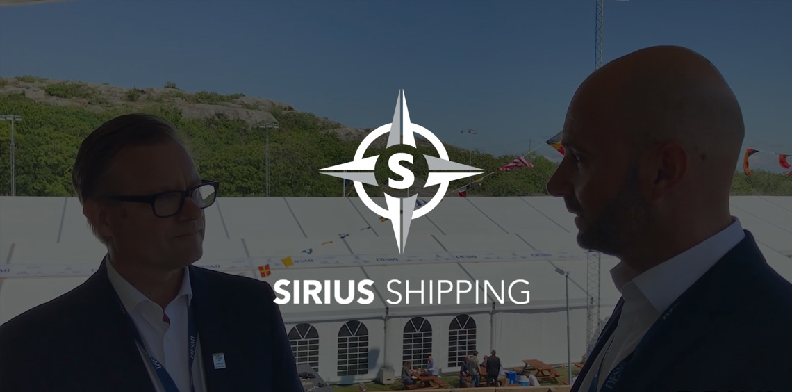 Two men conversing outdoors with Sirius Shipping and DESMI logos visible.