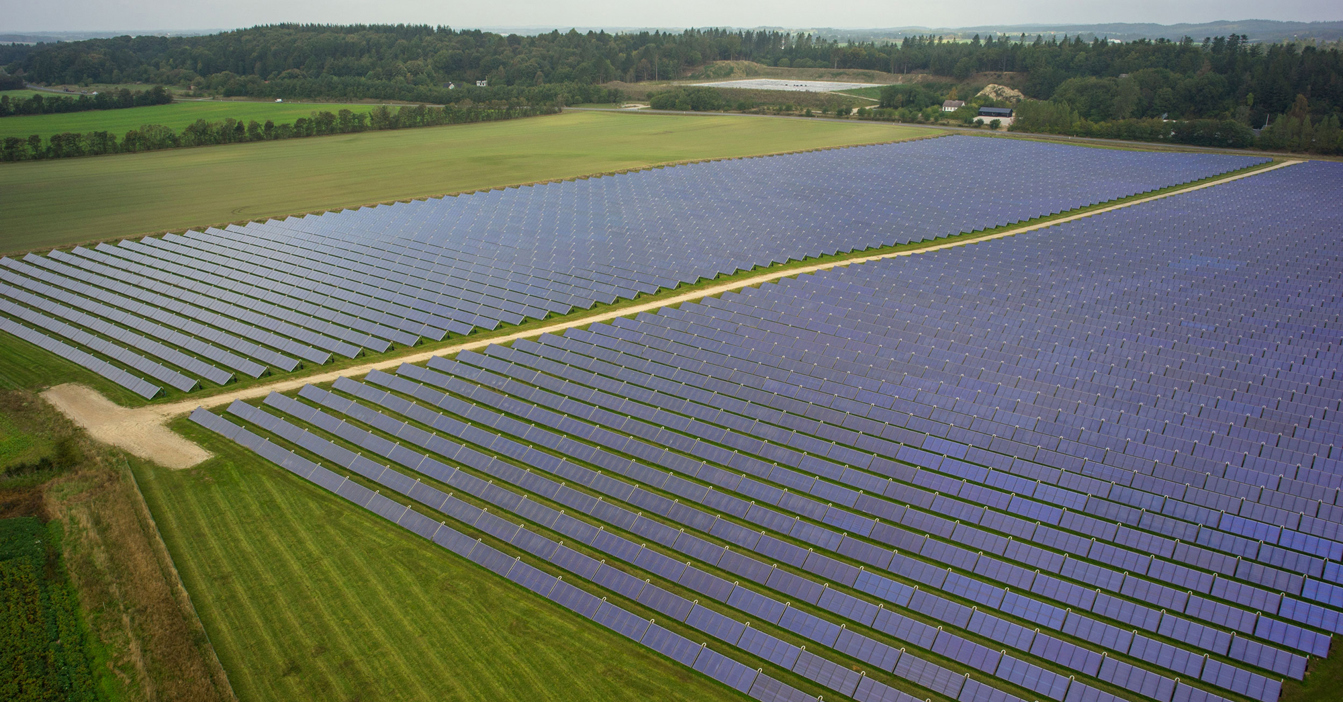在多云天空下的乡村景观中，广阔的太阳能电池板场地。