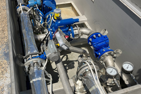 Blue industrial pumps and gauges in a metal enclosure for fluid handling.