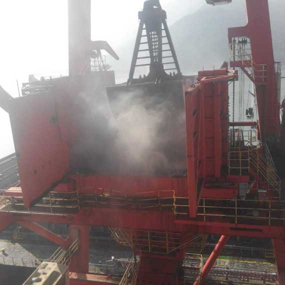 工业起重机在卸货，背景朦胧，可见烟雾。