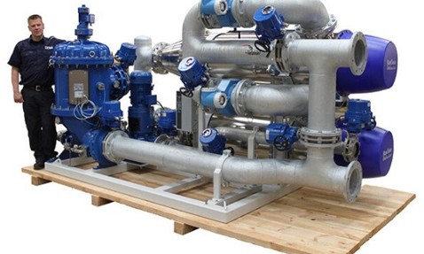 Large industrial DESMI pump system on wooden platform with a person standing nearby.