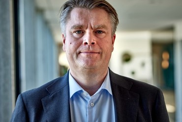 身穿西装的男子站在光线充足的走廊里。