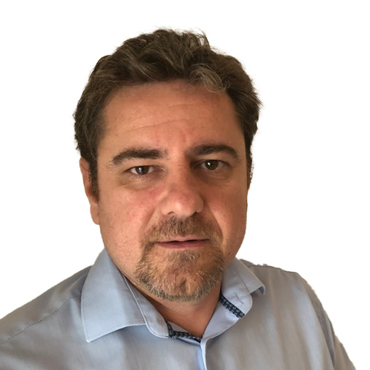 Homme avec des cheveux courts et une barbe portant une chemise à col bleu clair.