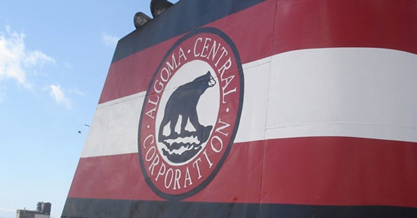 Fumaiolo della nave Algoma Central Corporation con logo su sfondo di cielo azzurro.